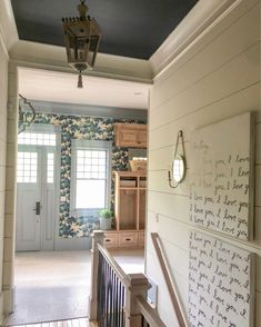 the hallway is decorated with blue and white wallpaper, along with wooden stairs that lead up to an open door