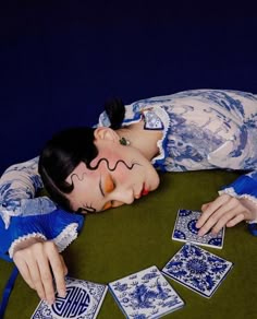 a woman laying on top of a table with playing cards in front of her face