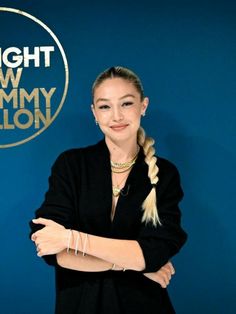 a woman standing in front of a blue wall with her arms crossed and the words tonight show jimmy lion on it