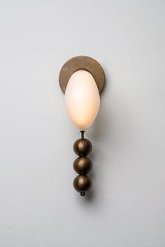 a wall mounted light on the side of a white wall with two balls attached to it