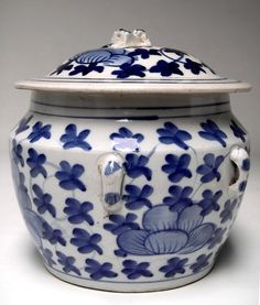 a blue and white vase with a lid on the top is sitting in front of a gray background