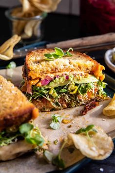 a sandwich cut in half sitting on top of a cutting board next to some chips