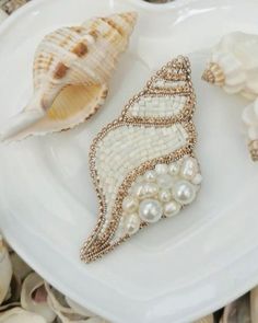 three seashells are sitting on a plate with pearls and other sea shells around them