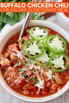 a white bowl filled with chili and cheese topped with sliced jalapeno peppers