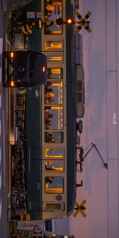 an overhead view of a train on the tracks with yellow and black lights at night