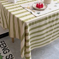 a green and white striped table cloth with two strawberries on it next to a box of milk