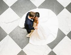 a bride and groom sitting on top of a checkered floor