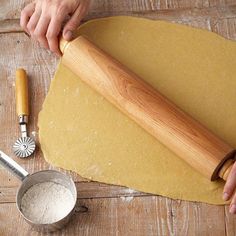 a person rolling dough on top of a wooden table