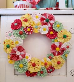 a wreath made out of paper flowers sitting on top of a dresser