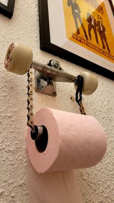 a pink toilet paper roll hanging on the wall next to a pair of rollers