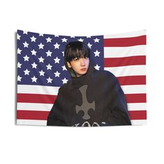 a person wearing a hoodie and standing in front of an american flag wall tapestry