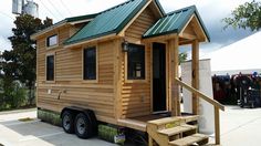 a tiny house on wheels with stairs leading up to the front door and green roof