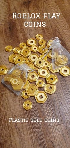 plastic gold coins sitting on top of a wooden floor next to a bag with the words roblox play coins