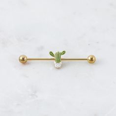 a gold bar with a green cactus on the top and two balls in the middle