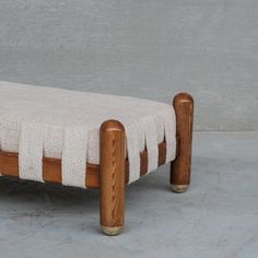 a wooden bench with a white blanket on it's back and two metal legs