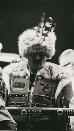 a black and white photo of a man wearing a fur hat with his hands in the air