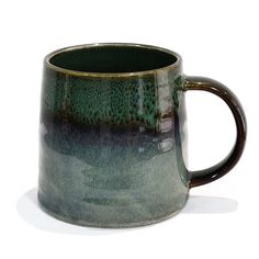 a green and black coffee mug sitting on top of a table