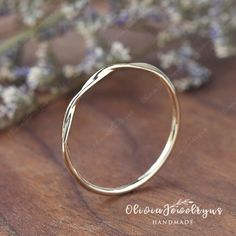 a gold ring sitting on top of a wooden table next to some lavenders and flowers