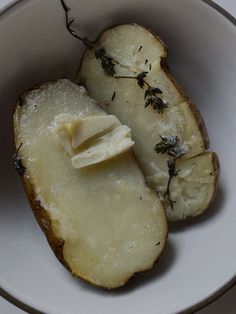 a white bowl filled with sliced potatoes covered in butter