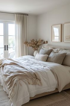 a large bed sitting in a bedroom next to a window covered in white linens