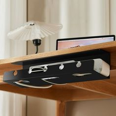 a laptop computer sitting on top of a wooden desk next to a light fixture and lamp