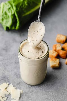 a spoon full of cream sitting next to some bread cubes and lettuce