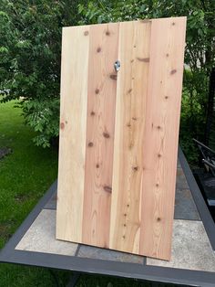 a wooden door sitting on top of a table in front of some grass and trees