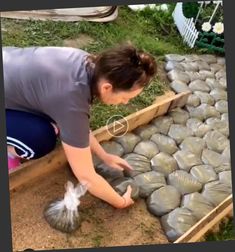 a woman kneeling down next to a pile of bags filled with rocks and gravel on the ground