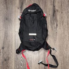 a black and red backpack sitting on top of a wooden floor