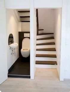 there is a toilet and sink in the bathroom with stairs leading up to the second floor