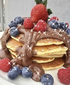 a stack of pancakes covered in chocolate and berries