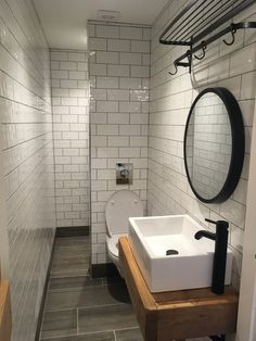 a white toilet sitting next to a sink in a bathroom under a mirror on the wall