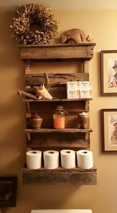 a toilet in a bathroom next to two shelves with items on them and pictures above it