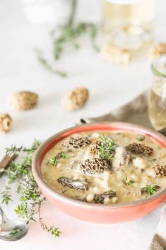 a bowl of soup with mushrooms and parsley on the side next to a spoon