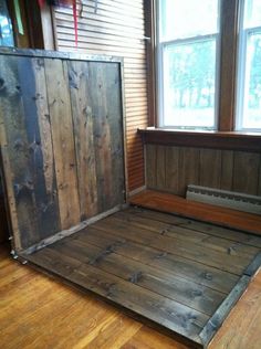 an empty bed frame in front of a window with wooden slats on the floor