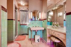 a bathroom with pink and green tiles on the walls, floor, and vanity area