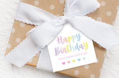 a gift wrapped in brown paper with a white ribbon and tag that says happy birthday