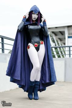 a woman dressed in costume is walking down the street with her cape over her head