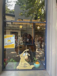 a woman is looking at her cell phone through the glass window in front of a store