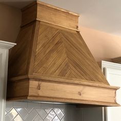 a wooden stove hood in a kitchen with white cabinets