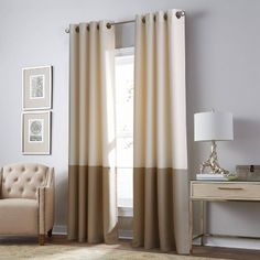 a living room filled with furniture and a large window covered in beige drapes next to a chair