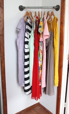 there are many different colored shirts hanging on the rack in this closet, and one is not