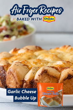 a close up of a cake on a plate near a bowl of salad and a bag of dinner rolls