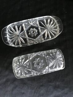 two glass salt and pepper shakers on a black tableclothed surface, one with an ornate design