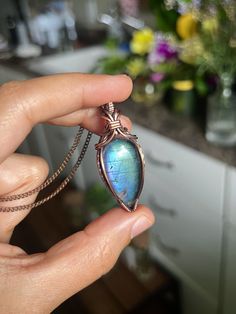 a person holding a necklace with a blue stone in it