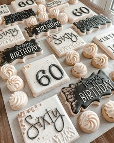 a table topped with lots of cookies covered in frosting and black lettering on top of each cookie