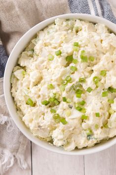 a white bowl filled with mashed potatoes and green onions