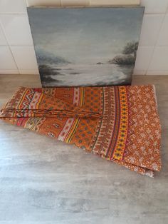 two pieces of cloth sitting on the floor next to a painting