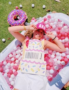 a woman laying in an inflatable pool with donuts and balloons around her