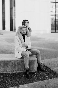 a man and woman are sitting on concrete steps outside an office building, one is holding the other's head